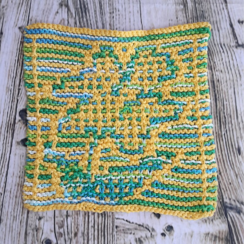 May include: A knitted dishcloth in yellow, green, blue, and white. The dishcloth has a geometric pattern.