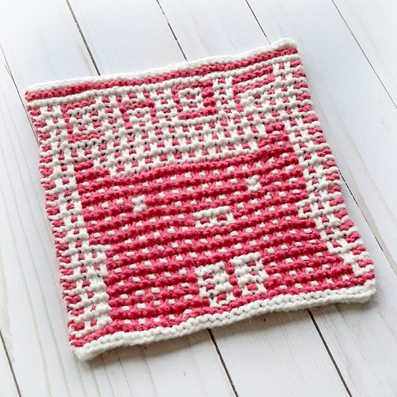 May include: A pink and white knitted dishcloth with a textured pattern.