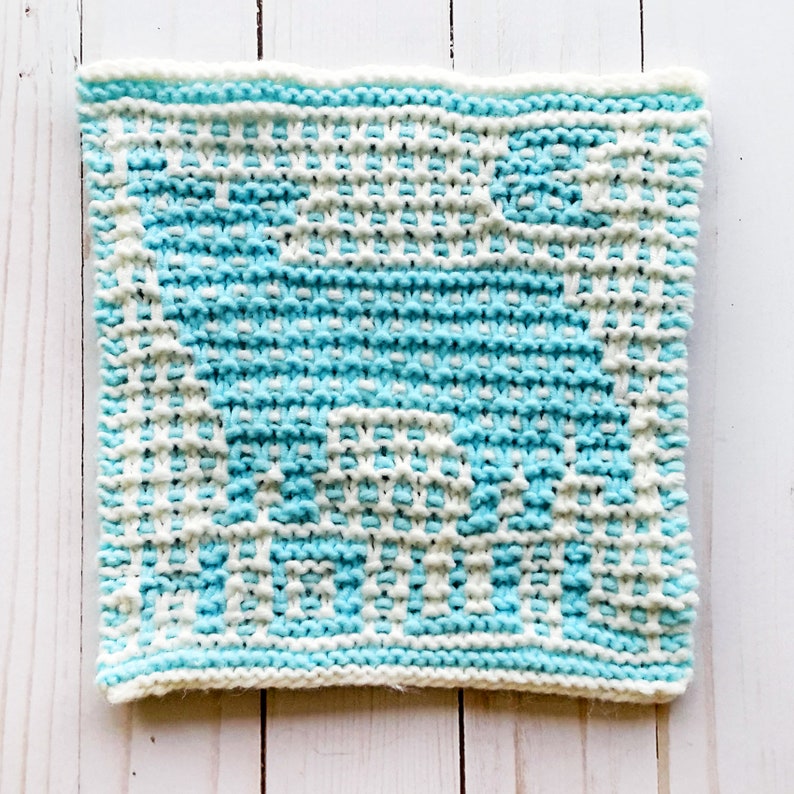 May include: A knitted dishcloth with a blue and white geometric pattern. The pattern is a simple design of squares and rectangles.