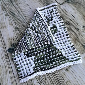 May include: A white and green knitted dishcloth with a textured pattern. The dishcloth is folded in half and has a white border.