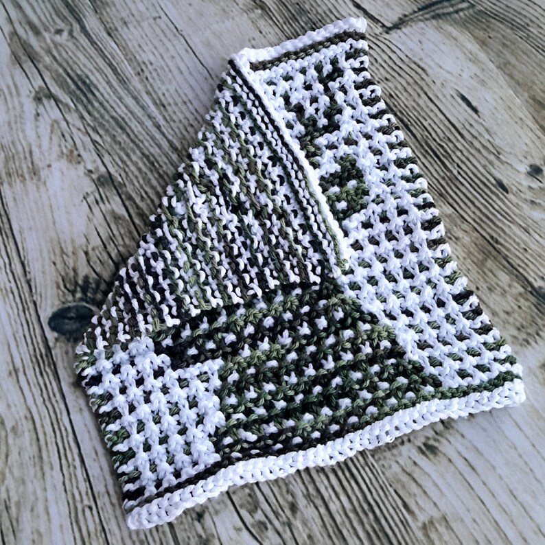 May include: A white and green knitted dishcloth with a textured pattern. The dishcloth is folded in half and has a white border.