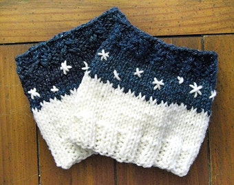 May include: A pair of knitted leg warmers with a white bottom and a dark blue top with white snowflake embroidery.