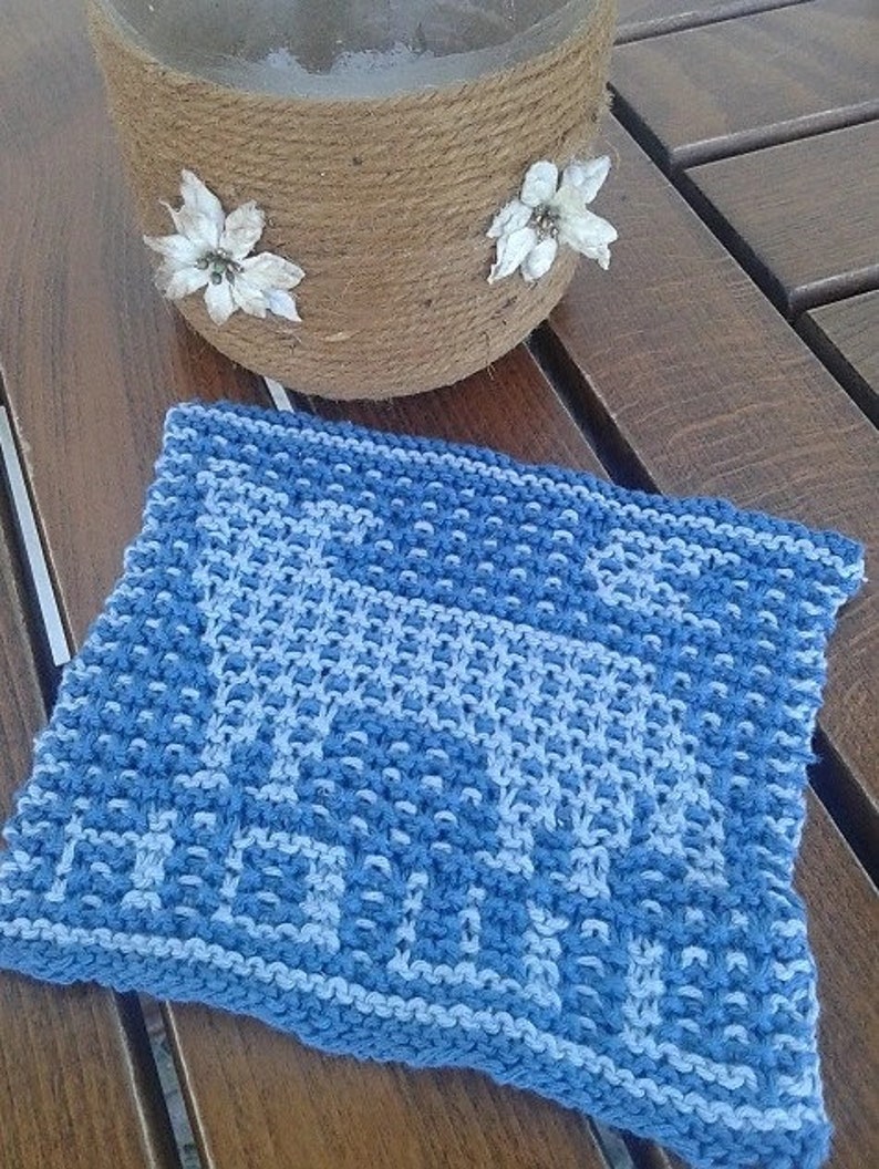 May include: A blue and white knitted dishcloth with a geometric pattern. The dishcloth is made of cotton and is ideal for drying dishes or cleaning surfaces.