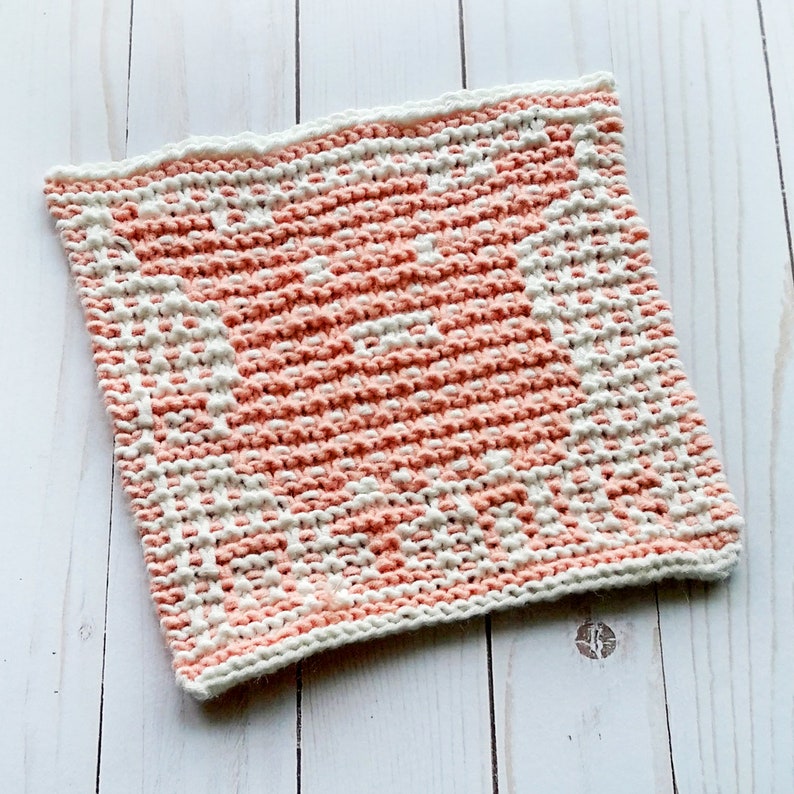 K&ouml;nnte beinhalten: Ein gestrickter Geschirrtuch mit einem geometrischen Muster in Rosa und Wei&szlig;. Das Geschirrtuch ist aus weichem, saugf&auml;higem Garn gefertigt und eignet sich perfekt zum Abwaschen von Geschirr oder zum Trocknen der H&auml;nde.