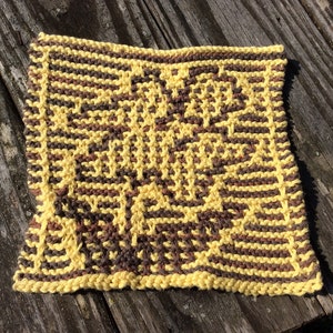 May include: A yellow and brown knitted dishcloth with a geometric pattern.