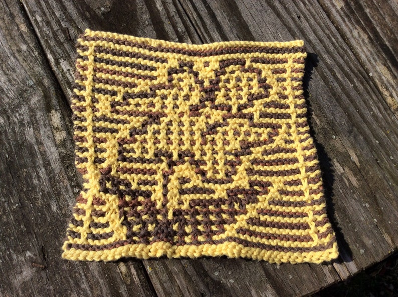 May include: A yellow and brown knitted dishcloth with a geometric pattern.