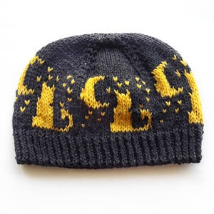 May include: A black knitted beanie with a yellow knitted design of the word "ALIVE".