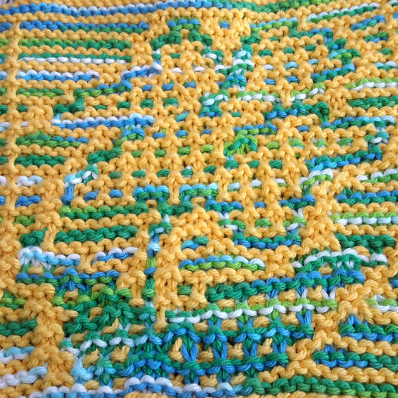 May include: A knitted dishcloth with a yellow, green, blue and white pattern. The dishcloth is made with a simple knit stitch and has a square shape.