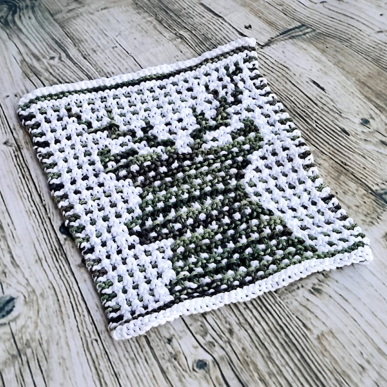 May include: A white and green knitted dishcloth with a geometric pattern.