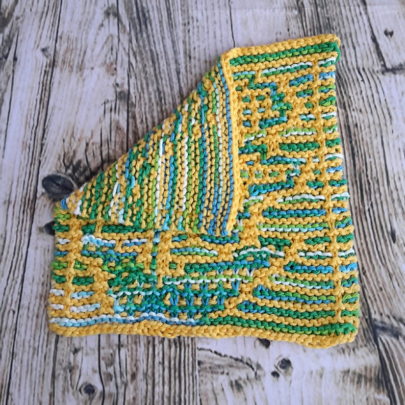 May include: A yellow, green and blue knitted dishcloth with a geometric pattern.