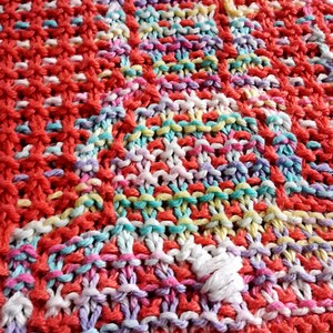 May include: A colorful knitted dishcloth with a variety of colors including red, pink, yellow, blue, and white.