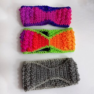 May include: Three crocheted headbands in different colours and patterns. The top headband is purple, pink, and blue. The middle headband is green, orange, pink, and red. The bottom headband is grey.
