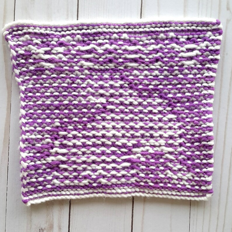 Puede incluir: Un pa&ntilde;o de cocina de punto morado y blanco con un patr&oacute;n texturizado.