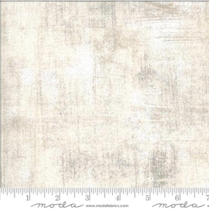 May include: Cream-colored fabric with a textured, distressed appearance. The fabric has a mottled effect with subtle variations in tone, and a ruler is visible along the bottom edge. The fabric is suitable for quilting and other craft projects.