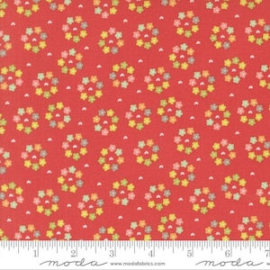 May include: Red fabric with a repeating pattern of small, multi-colored flower wreaths. The fabric is marked with a ruler in inches.