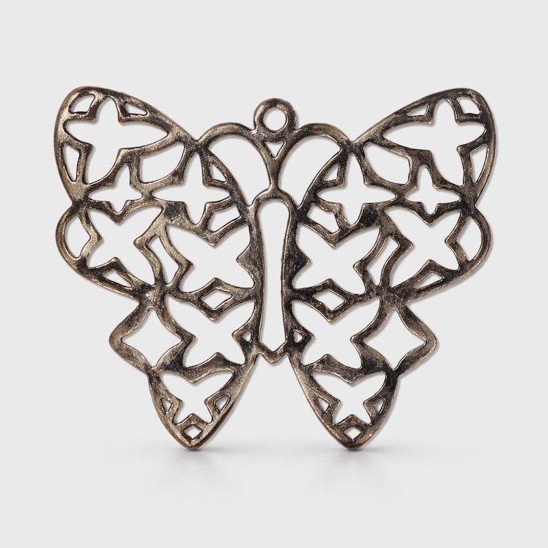 May include: A silver-colored butterfly pendant with a cutout design. The wings are adorned with cross-shaped cutouts, and the body has a vertical cutout. The pendant has a small loop at the top for hanging.