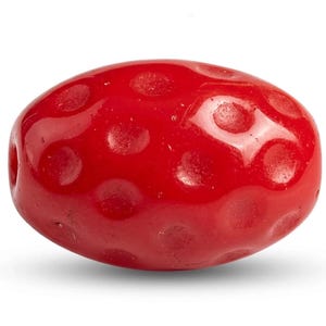 Könnte beinhalten: Eine leuchtend rote, ovale Perle mit glänzender Oberfläche. Die Perle weist ein Muster aus gleichmäßig verteilten, vertieften Kreisen auf ihrer Oberfläche auf. Das Design deutet auf ein dekoratives Element hin, möglicherweise für Schmuck oder Bastelarbeiten.