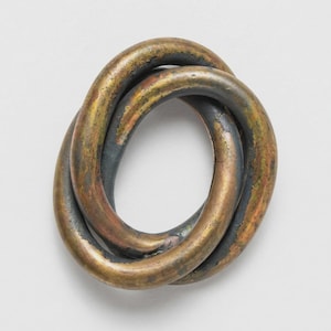 May include: A bronze-colored metal sculpture in a knotted design. The sculpture has a weathered appearance with shades of gold, brown, and dark gray. The intertwined loops create an abstract, three-dimensional form.