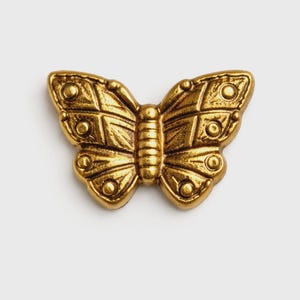 May include: A detailed, golden butterfly ornament with intricate patterns on its wings and body. The butterfly is centered on a white background, showcasing its metallic sheen and textured surface. This decorative piece could be used for jewelry or crafts.