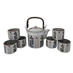 May include: A ceramic tea set consisting of one teapot with a woven handle and five matching cups. Each piece features a light gray base with a repeating pattern of vertical stems, dark blue leaves, and small red dots arranged in a column design.