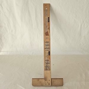 May include: A vintage wooden T-square with printed charts and text. The T-square is made of light-coloured wood and has a rectangular head and a long, narrow blade. The blade has a hole at the top and printed information along its length.