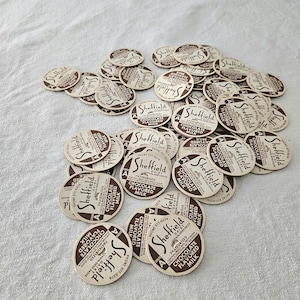 May include: A collection of vintage Sheffield Dairy chocolate flavored milk bottle caps. The caps are circular with a brown and cream color scheme. The text "Sheffield" and "Chocolate Flavored Milk" are printed on each cap.