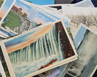 May include: A collection of vintage postcards featuring scenic views. One postcard shows Niagara Falls with the text "THE FALLS FROM DECK OF MAID OF THE MIST NIAGARA FALLS." Other cards depict fountains and landscapes.