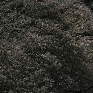 以下が含まれることがあります： 暗く粒状の物質のクローズアップ。テクスチャは粗く不均一で、マットな仕上がりです。色は深いチャコールブラックで、微妙な色の変化があります。全体的な印象は、密度が高く、固い物質です。