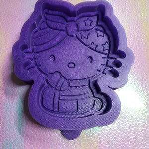 Puede incluir: Molde de silicona morado de un personaje de dibujos animados que lleva una bandana roja, blanca y azul con estrellas. El personaje lleva un atuendo rojo, blanco y azul con un lazo blanco.
