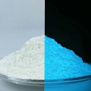 Könnte beinhalten: Ein geteiltes Bild zeigt einen Haufen weißes Pulver auf einer klaren Glasplatte, im Kontrast zu demselben Pulver, das hellblau leuchtet. Das Pulver ist fein und scheint ein lumineszierendes Material zu sein.