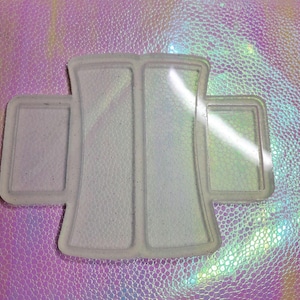 May include: A white silicone mold with three rectangular sections. The mold is designed to create resin crafts.
