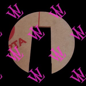 May include: A clear, semi-circular acrylic piece with a rectangular cutout. The piece has a light brown hue and a red line running down the center. The letters "PTA" are visible on the left side. The background is black with repeating pink "W" patterns.