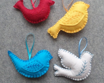 Peut inclure: Quatre ornements d'oiseaux en feutrine rouge, jaune, bleue et blanche. Chaque oiseau présente des détails d'ailes cousus et une boucle en ruban assortie pour suspendre. L'oiseau rouge a un ruban rouge, le jaune un orange, le bleu un bleu et le blanc un bleu.