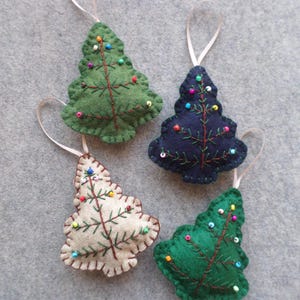 May include: Four felt Christmas tree ornaments in olive green, navy blue, cream, and forest green. Each tree features brown embroidered branches and small, colorful seed beads acting as ornaments, finished with a thin ribbon loop for hanging.