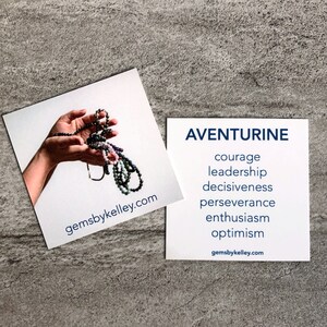 May include: Two square cards featuring jewelry and text. One card shows a hand holding beaded necklaces with the text gemsbykelley.com. The other card displays the word AVENTURINE in blue, followed by the words courage, leadership, decisiveness, perseverance, enthusiasm, and optimism, with gemsbykelley.com at the bottom.