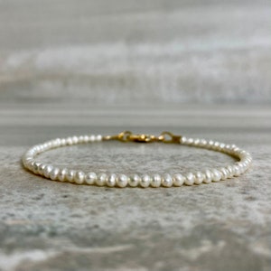 May include: A delicate pearl bracelet with a gold clasp. The bracelet is made of small, white pearls and is perfect for everyday wear.