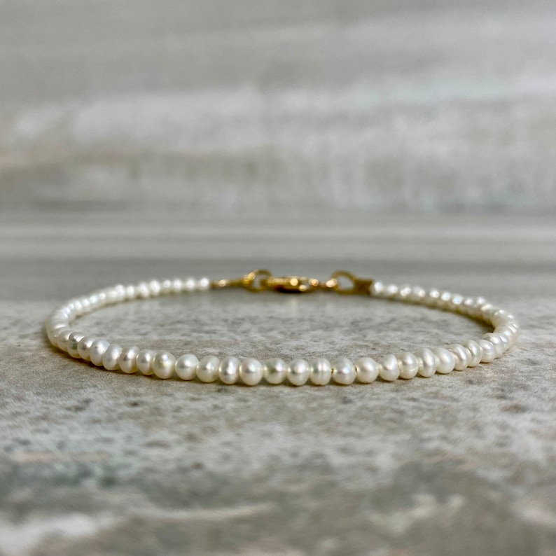 May include: A delicate pearl bracelet with a gold clasp. The bracelet is made of small, white pearls and is perfect for everyday wear.