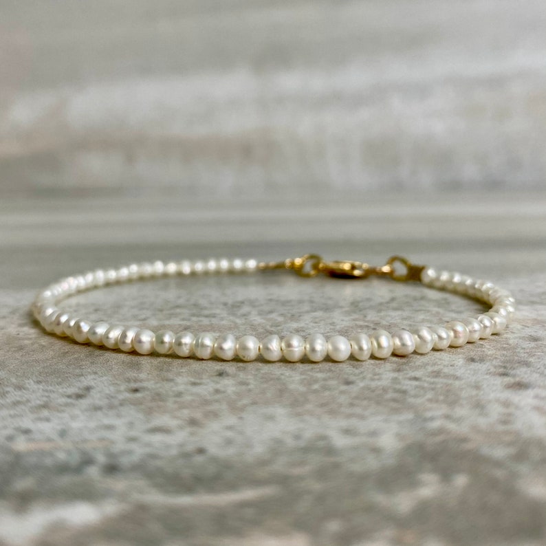 May include: A delicate pearl bracelet with a gold clasp. The bracelet is made of small, white pearls and is perfect for everyday wear.