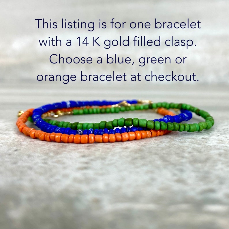 May include: Three beaded bracelets in orange, green, and blue with a gold filled clasp.  "This listing is for one bracelet with a 14 K gold filled clasp. Choose a blue, green or orange bracelet at checkout."