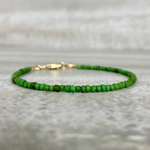 May include: A delicate green beaded bracelet with a gold clasp.