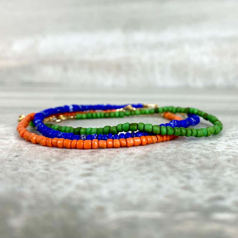May include: A layered beaded bracelet with orange, green and blue beads.