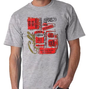 May include: A gray t-shirt with a graphic design featuring the word "GOLD" in a distressed font. The design includes red rectangles with text, a gold nugget illustration, and the phrases "Feel the Rush" and "Gold Rush."