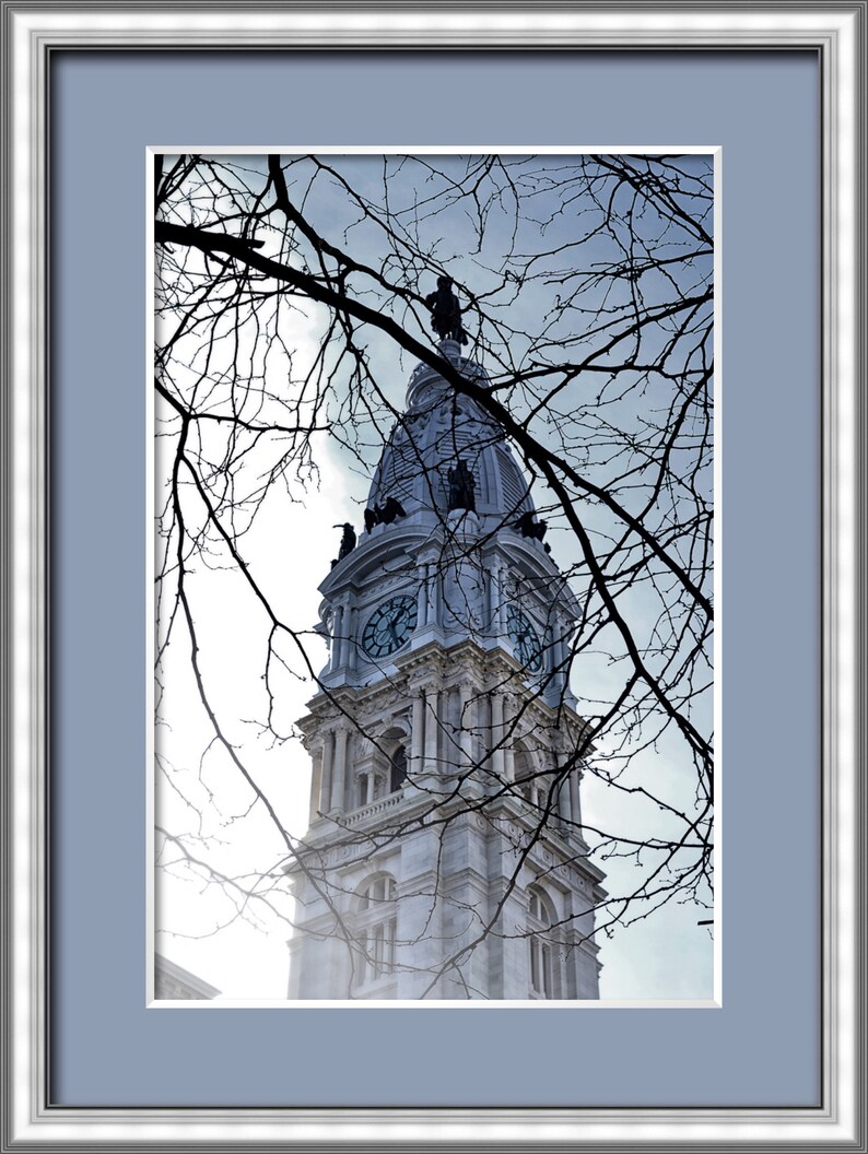 K&ouml;nnte beinhalten: Eine Nahaufnahme des Uhrturms des Philadelphia City Hall, mit kahlen &Auml;sten im Vordergrund.