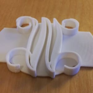 May include: White plastic cookie cutter shaped like the letter "W" with decorative flourishes.