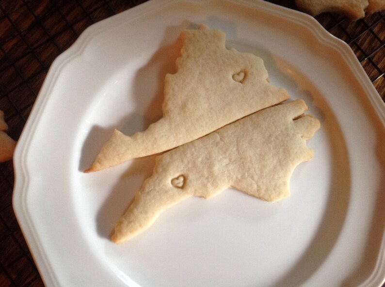 May include: Two sugar cookies shaped like a state outline with a heart cutout on each cookie.