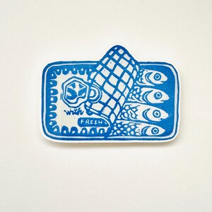Op de afbeelding: Blauw-witte linosnede van een blikje sardines met de tekst "with fresh" op het etiket.