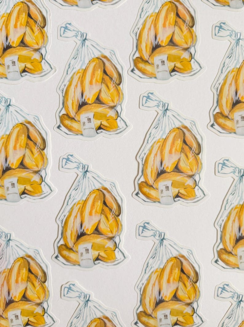 Op de afbeelding: Een vel stickers met een herhalend patroon van gele stokbroden in doorzichtige plastic zakken. Elke zak heeft een wit prijskaartje.