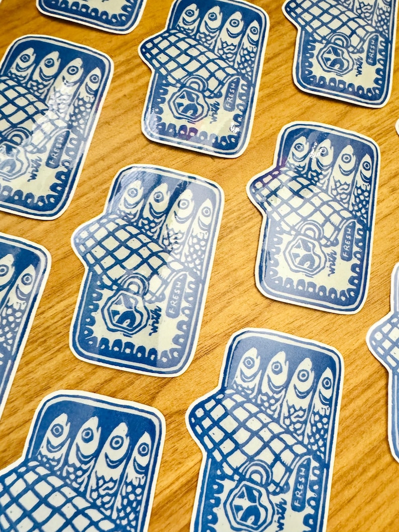 Op de afbeelding: Een set blauwe en witte stickers met een gestileerde illustratie van een blikje sardines. Het blikje is open en de sardines zijn zichtbaar in het blikje. De tekst "Fresh With A Twist" is op het blikje gedrukt.