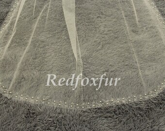 May include: A white bridal veil with a beaded edge. The veil is made of soft tulle and has a delicate floral pattern.