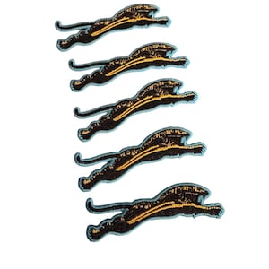 May include: Five black and gold embroidered iron-on patches of a leaping panther.